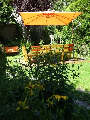 an orange umbrella and bench in a garden at Chalet des Glaciers in Chamonix-Mont-Blanc