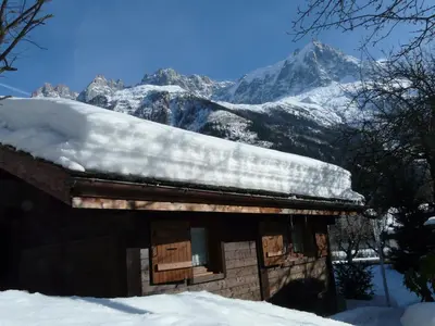 a snow covered cabin with a mountain in the background at Chalet des Glaciers in Chamonix-Mont-Blanc