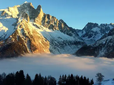 a mountain covered in snow with a layer of clouds at Appartement Duplex Forclaz in Chamonix-Mont-Blanc