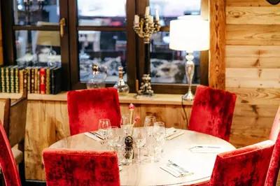 a table in a restaurant with red chairs and a table with glasses at Hotel Le Castel in Chamonix-Mont-Blanc
