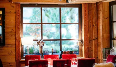 a room with a table with red chairs and a window at Hotel Le Castel in Chamonix-Mont-Blanc