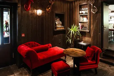 a living room with a red couch and a table at Hotel Le Castel in Chamonix-Mont-Blanc