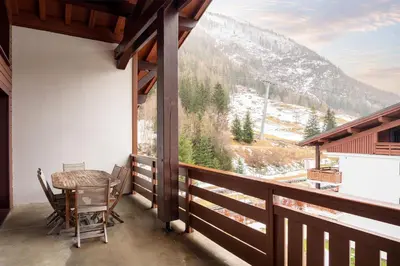 a balcony with a table and chairs and a view at Dormio Resort Les Portes du Mont Blanc in Vallorcine