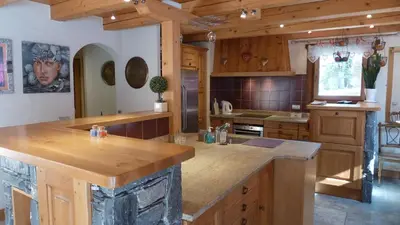 a kitchen with wooden cabinets and a large island at Chalet KIDOU, Grand Confort, nouveau SPA extérieur in Chamonix-Mont-Blanc