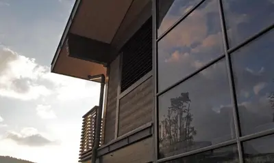 a building with a reflection of a tree in the windows at La Croix de Savoie & Spa in Les Carroz d'Araches