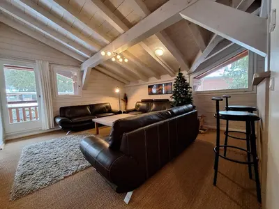 a living room with leather furniture and a christmas tree at Chalet Hideaway 2 in Chamonix-Mont-Blanc