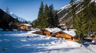 a log cabin in the snow with trees and mountains at Chalet Hideaway 2 in Chamonix-Mont-Blanc