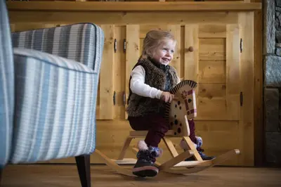 a little girl is sitting on a wooden chair at CGH Résidence Boutique Les Chalets de Léana in Les Carroz d'Araches