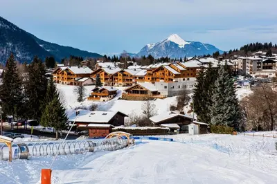 a snow covered town with a mountain in the background at CGH Résidence Boutique Les Chalets de Léana in Les Carroz d'Araches