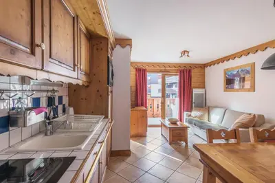 a kitchen and living room with a couch at Residence Les Fermes du Soleil - maeva Home in Les Carroz d'Araches