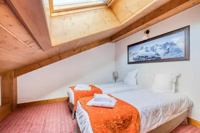 a bedroom with two beds and a tv on the wall at Residence Les Fermes du Soleil - maeva Home in Les Carroz d'Araches