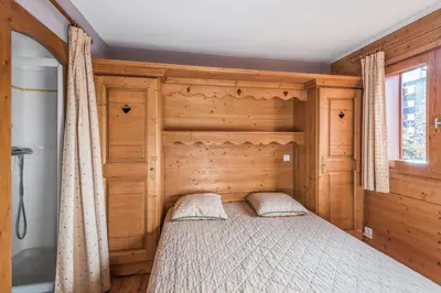 a bedroom with a bed with a wooden headboard at Residence Les Fermes du Soleil - maeva Home in Les Carroz d'Araches