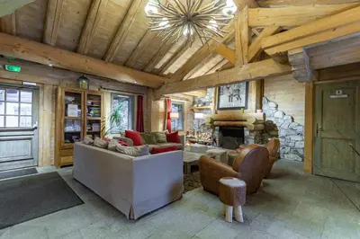 a living room with couches and a stone fireplace at Residence Les Fermes du Soleil - maeva Home in Les Carroz d'Araches