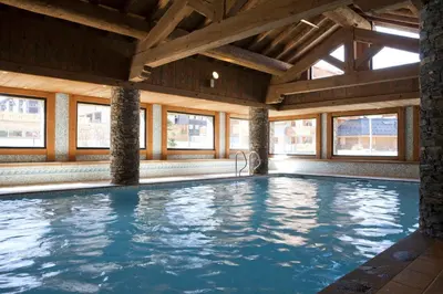 a swimming pool in a building with windows at Residence Les Fermes du Soleil - maeva Home in Les Carroz d'Araches