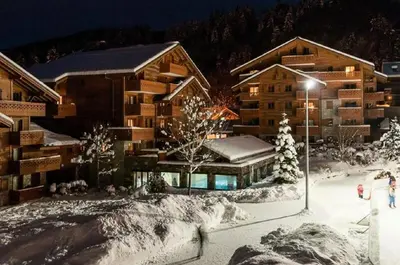 a ski lodge in the snow at night at Residence Les Fermes du Soleil - maeva Home in Les Carroz d'Araches
