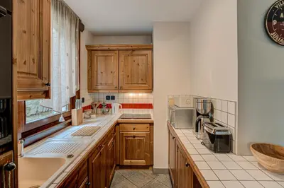 a kitchen with wooden cabinets and a counter top at APARTMENT STADDON - Alpes Travel - Central Chamonix - Sleeps 4-6 in Chamonix-Mont-Blanc