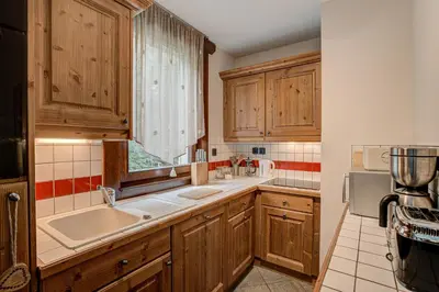 a kitchen with wooden cabinets and a sink and a window at APARTMENT STADDON - Alpes Travel - Central Chamonix - Sleeps 4-6 in Chamonix-Mont-Blanc