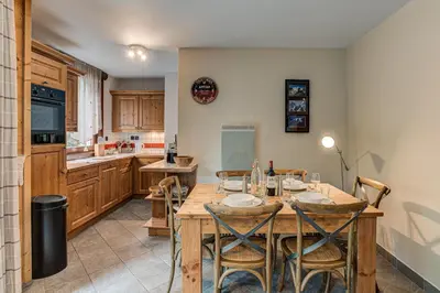a kitchen with a wooden table and some chairs at APARTMENT STADDON - Alpes Travel - Central Chamonix - Sleeps 4-6 in Chamonix-Mont-Blanc