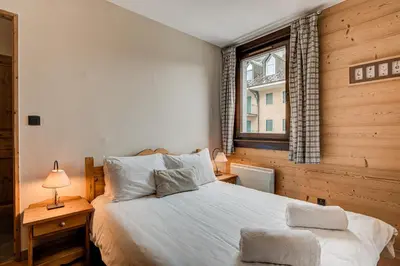 a bedroom with a large white bed and a window at APARTMENT STADDON - Alpes Travel - Central Chamonix - Sleeps 4-6 in Chamonix-Mont-Blanc
