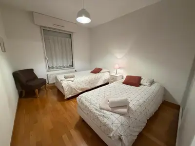 a bedroom with two beds and a chair and a window at Appartement CITY CENTER-SALLANCHES in Sallanches