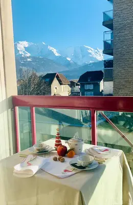 a table on a balcony with a view of a mountain at Appartement CITY CENTER-SALLANCHES in Sallanches
