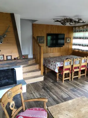 a living room with a table and chairs and a television at Chalets de Julie in Megève
