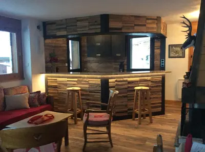 a living room with a kitchen and a bar with stools at Chalets de Julie in Megève