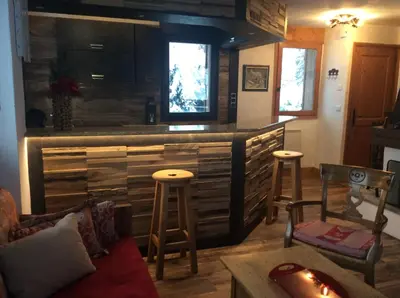 a living room with a bar with some stools at Chalets de Julie in Megève
