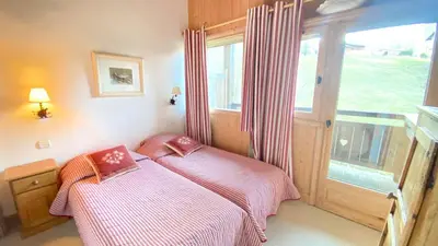a bedroom with two beds in front of a window at Chalets de Julie in Megève