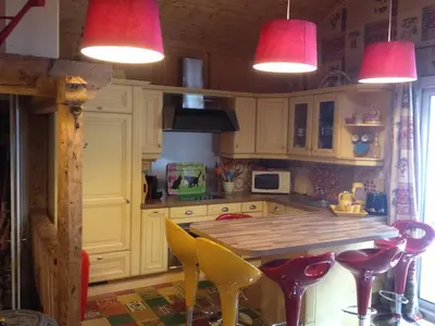 a kitchen with a wooden table and two pink lights at chalet des petits loups in Chamonix-Mont-Blanc