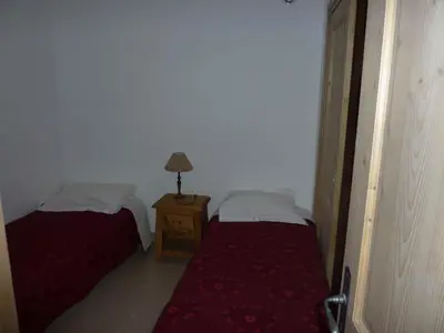 a room with two beds and a lamp on a table at Le Hameau des Neiges in Demi-Quartier