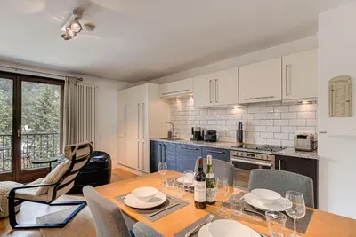 a kitchen with a wooden table and chairs and a kitchen with white cabinets at APARTMENT COSMIQUES - Alpes Travel - Central Chamonix - Sleeps 4 in Chamonix-Mont-Blanc