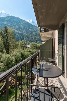 a table on a balcony with a view of mountains at APARTMENT COSMIQUES - Alpes Travel - Central Chamonix - Sleeps 4 in Chamonix-Mont-Blanc