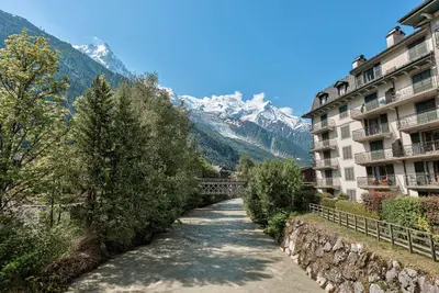 a road in the mountains next to a building at APARTMENT COSMIQUES - Alpes Travel - Central Chamonix - Sleeps 4 in Chamonix-Mont-Blanc