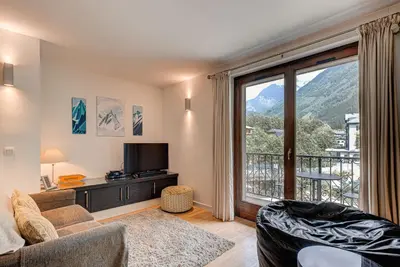 a living room with a couch and a large window at APARTMENT COSMIQUES - Alpes Travel - Central Chamonix - Sleeps 4 in Chamonix-Mont-Blanc