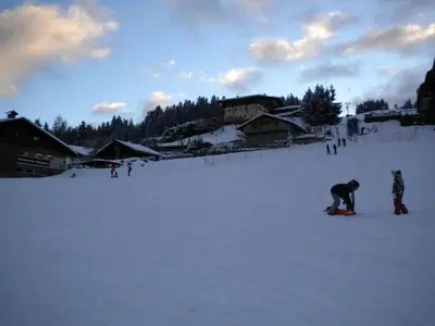 a couple of people on a snowboard in the snow at La Coupe De Cristal in Saint-Gervais-les-Bains