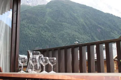 three wine glasses sitting on a table on a balcony at Apartment Mummery 1 - Central Chamonix Walk to Piste in Chamonix-Mont-Blanc
