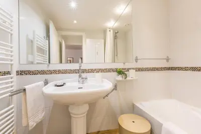 a white bathroom with a sink and a bath tub at Apartment Mummery 1 - Central Chamonix Walk to Piste in Chamonix-Mont-Blanc