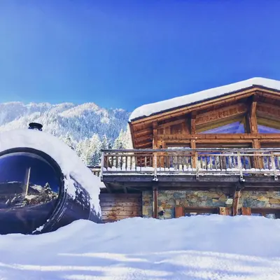 a snow covered log cabin with a snow covered porch at Marmotte Mountain Eco Lodge in Chamonix-Mont-Blanc