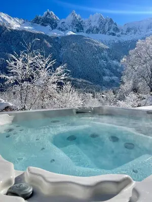 a hot tub with a view of snowy mountains at Marmotte Mountain Eco Lodge in Chamonix-Mont-Blanc