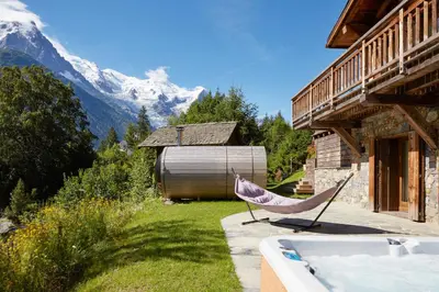 a hammock sitting on a patio next to a house at Marmotte Mountain Eco Lodge in Chamonix-Mont-Blanc