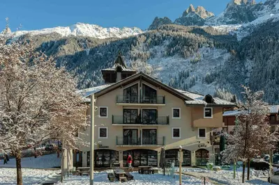 a large building with snow covered mountains in the background at Ginabelle 8 apartment - Chamonix All Year in Chamonix-Mont-Blanc