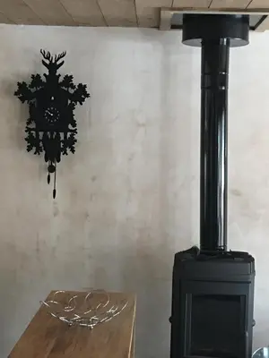 a black stove with a clock on a wall at Les Chalets Aquarelle in Chamonix-Mont-Blanc