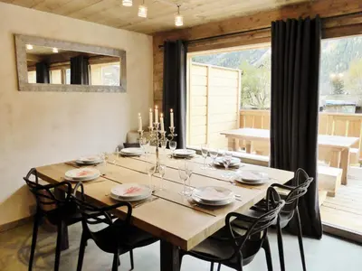 a dining room table with chairs and a large window at Les Chalets Aquarelle in Chamonix-Mont-Blanc