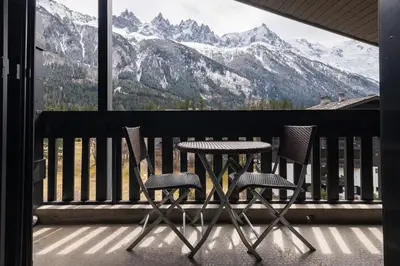 two chairs and a table on a balcony with mountains at APARTMENT LES DRUS - Alpes Travel - Chamonix - Sleeps 6 in Chamonix-Mont-Blanc
