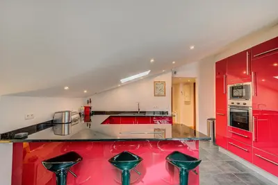 a red kitchen with a counter with stools at APARTMENT LES DRUS - Alpes Travel - Chamonix - Sleeps 6 in Chamonix-Mont-Blanc