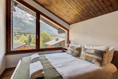 a bedroom with a large bed with a large window at APARTMENT CHAMOUNY - Alpes Travel - Chamonix - Sleeps 8 in Chamonix-Mont-Blanc