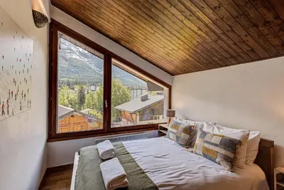 a bedroom with a bed and a large window at APARTMENT CHAMOUNY - Alpes Travel - Chamonix - Sleeps 8 in Chamonix-Mont-Blanc