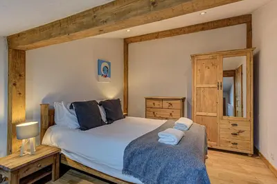 a bedroom with a large bed and a dresser at APARTMENT CHAMOUNY - Alpes Travel - Chamonix - Sleeps 8 in Chamonix-Mont-Blanc