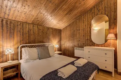 a bedroom with a bed with a wooden wall at APARTMENT CHAMOUNY - Alpes Travel - Chamonix - Sleeps 8 in Chamonix-Mont-Blanc